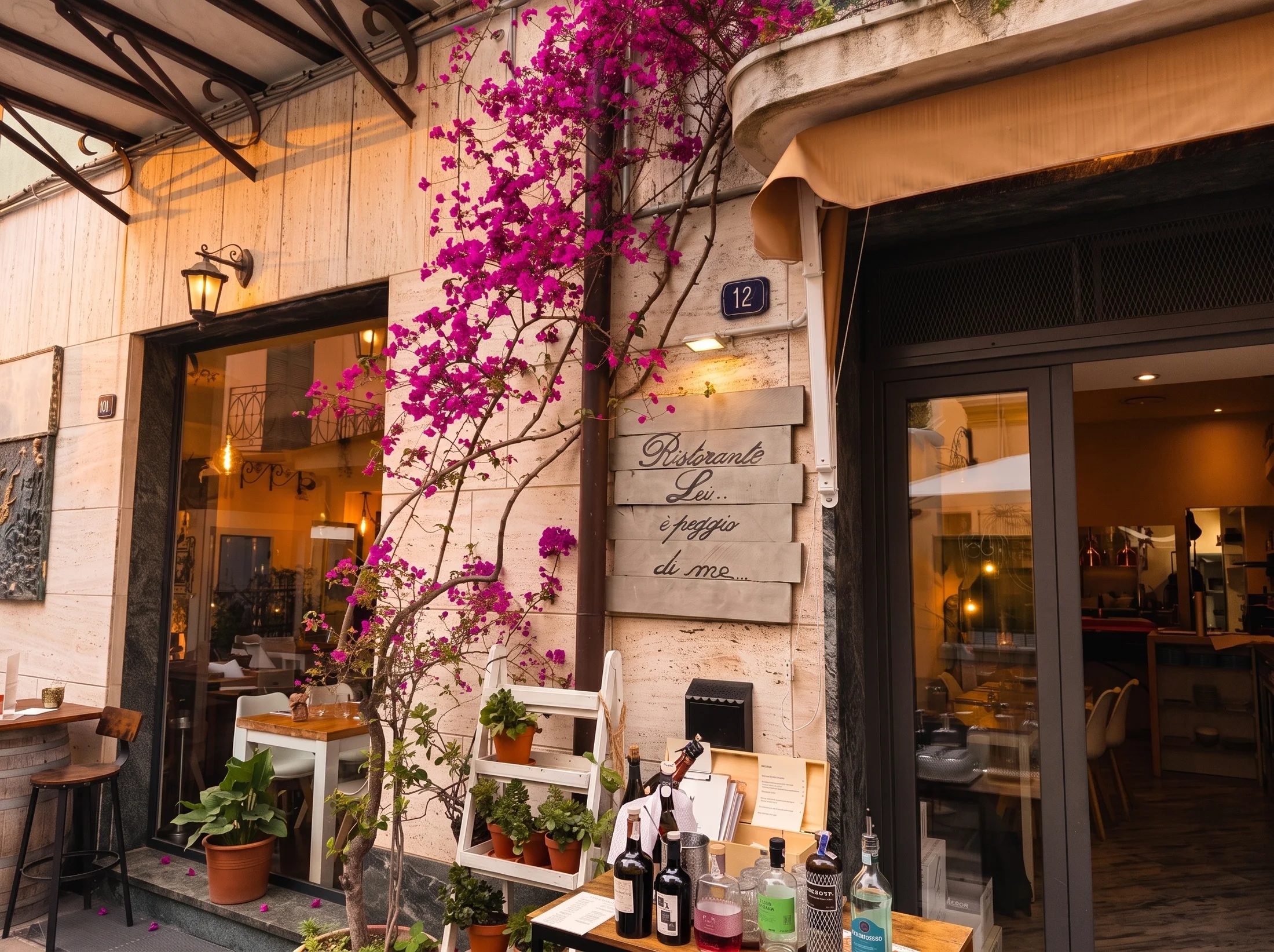 la facciata del ristorante nel caruggio di Spotorno, con l'insegna, la bouganville e la luce della sera